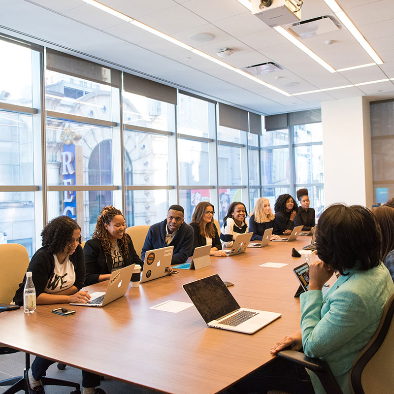 Corporate meeting with diverse professionals using laptops in a conference room in the USA
