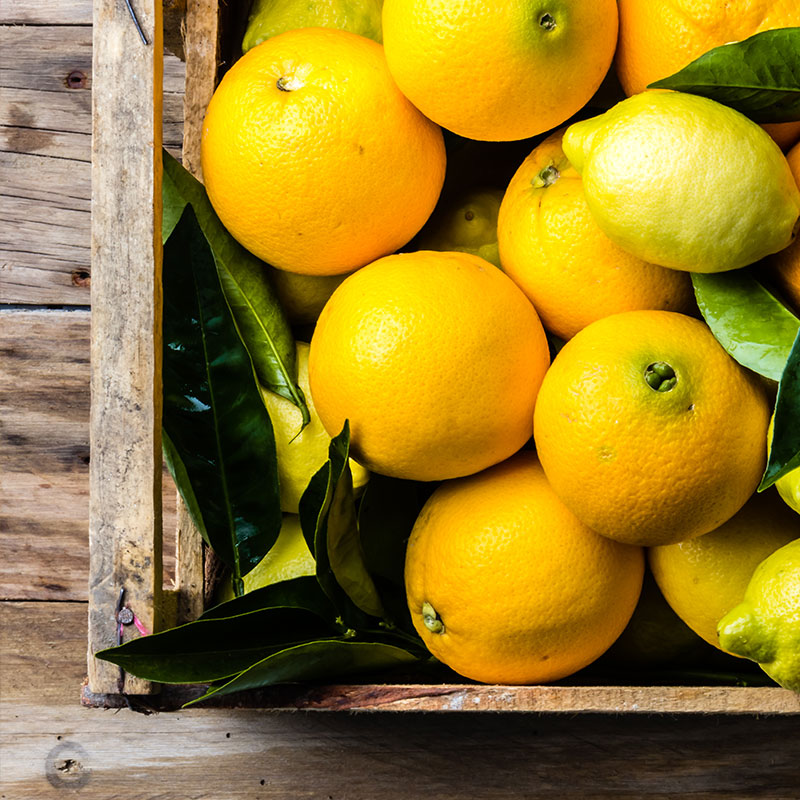Fresh lemons and oranges in a wooden crate on a rustic surface, sourced in the USA