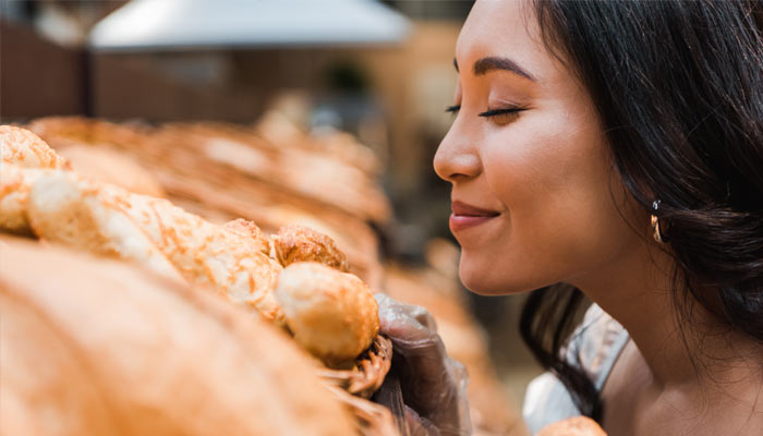 A woman smelling the fresh vegetables at a grocery store in the USA