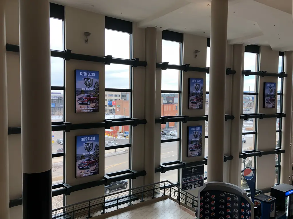 Large indoor stadium windows with advertisement screens and a view of the city outside in the USA.